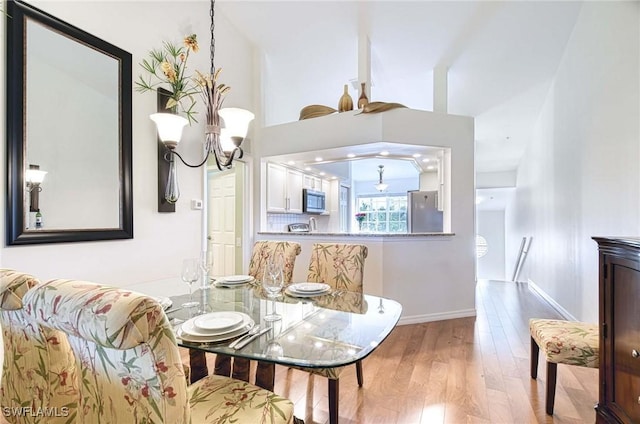 dining space with baseboards, wood finished floors, and an inviting chandelier