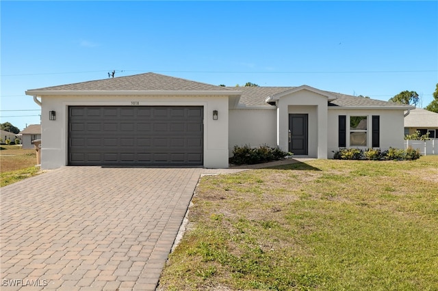 view of front of property featuring a garage, a front yard, decorative driveway, and stucco siding