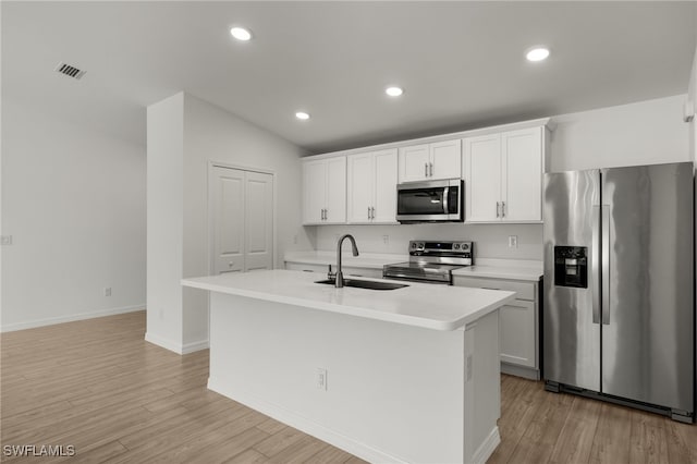 kitchen with stainless steel appliances, light wood-type flooring, a sink, and an island with sink