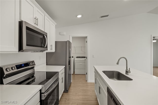 kitchen with a sink, visible vents, washer and dryer, white cabinets, and appliances with stainless steel finishes