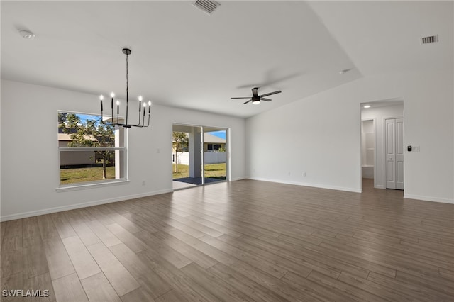 empty room featuring ceiling fan with notable chandelier, visible vents, baseboards, and wood finished floors