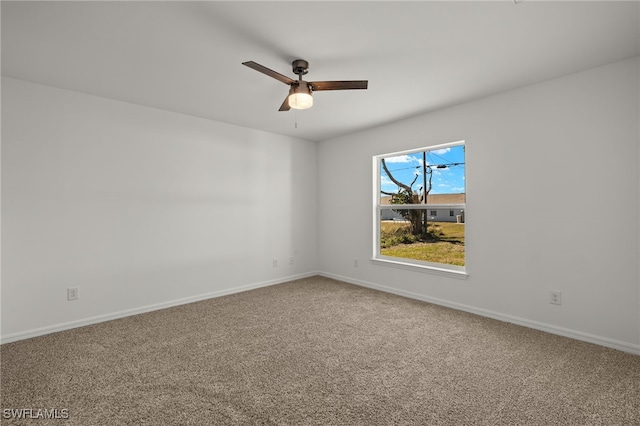 carpeted spare room featuring baseboards and a ceiling fan