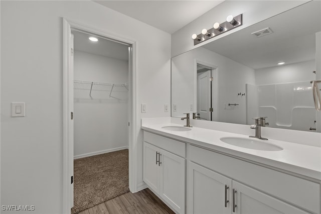 bathroom featuring a spacious closet, double vanity, a sink, and visible vents