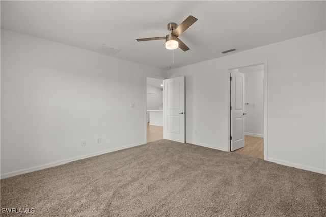 unfurnished bedroom with baseboards, ceiling fan, visible vents, and light colored carpet