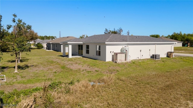 rear view of property with a lawn, cooling unit, and stucco siding