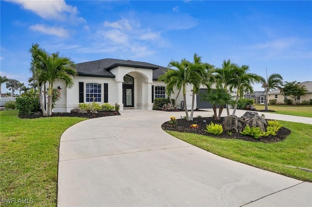 view of front of house featuring stucco siding, curved driveway, and a front yard