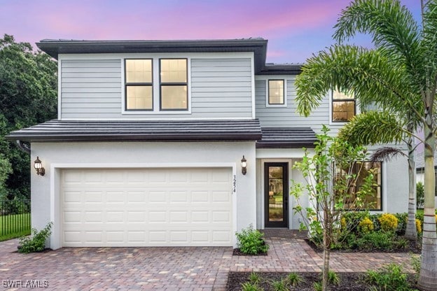 view of front of property with an attached garage, decorative driveway, and stucco siding