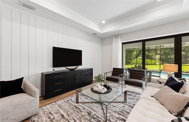 living room with crown molding, recessed lighting, a raised ceiling, visible vents, and light wood-style flooring