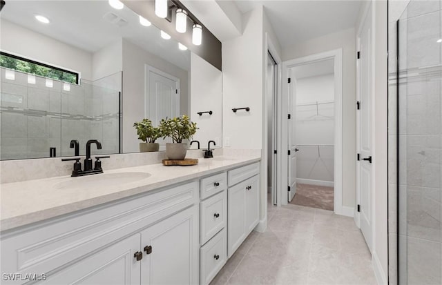 full bath with double vanity, a spacious closet, a sink, and tiled shower