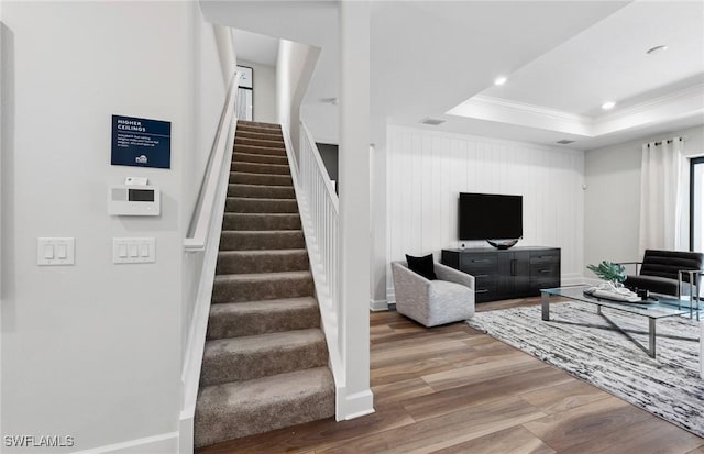 living room with a raised ceiling, stairway, ornamental molding, wood finished floors, and recessed lighting