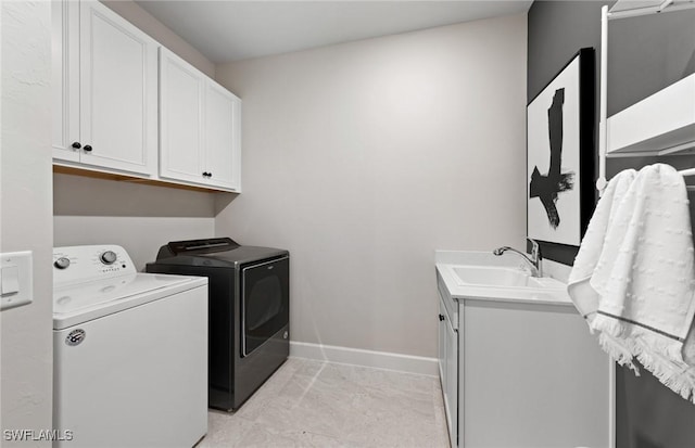 clothes washing area featuring a sink, washing machine and clothes dryer, cabinet space, and baseboards