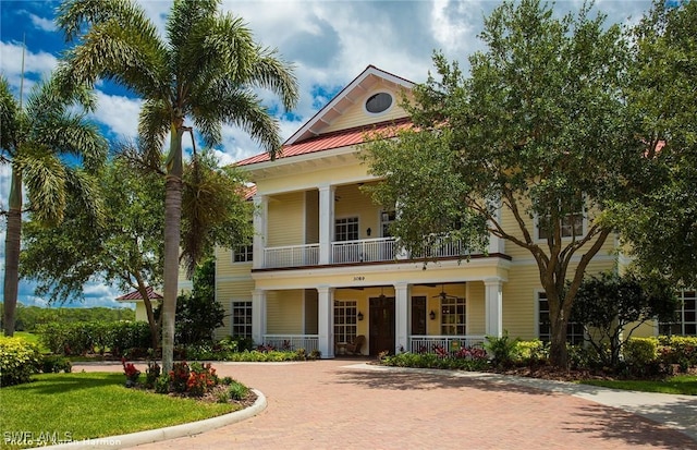 neoclassical home featuring a balcony, ceiling fan, metal roof, covered porch, and decorative driveway