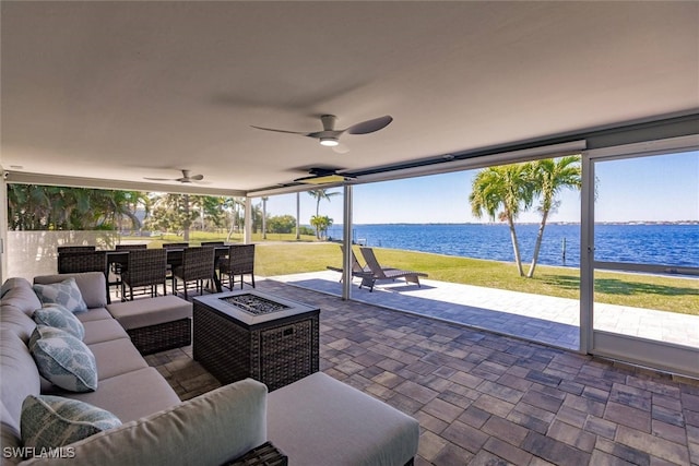 view of patio / terrace featuring an outdoor living space with a fire pit, a water view, and ceiling fan