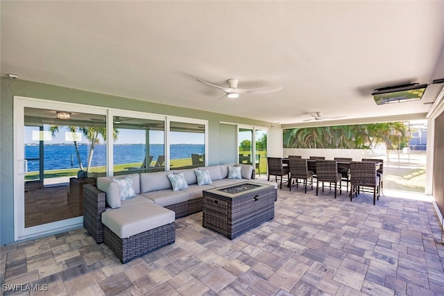 view of patio featuring a water view, ceiling fan, outdoor dining area, and an outdoor living space with a fire pit