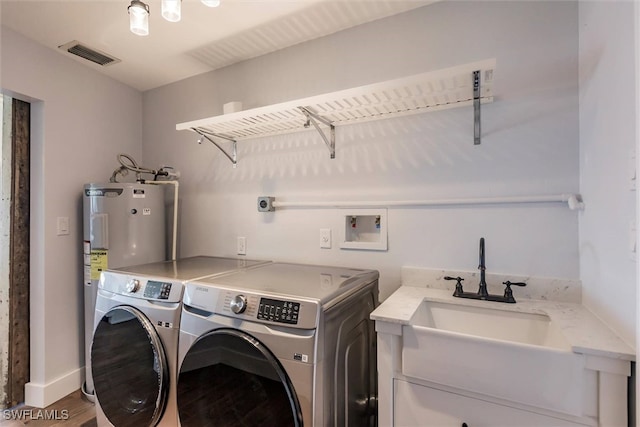 washroom with laundry area, visible vents, wood finished floors, washing machine and dryer, and a sink