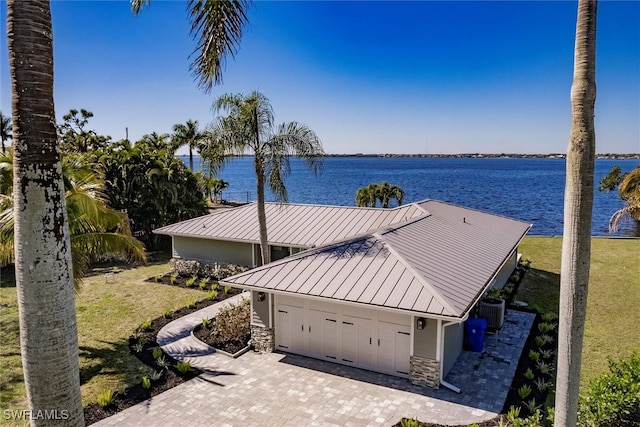 exterior space with stone siding, a standing seam roof, a water view, and metal roof