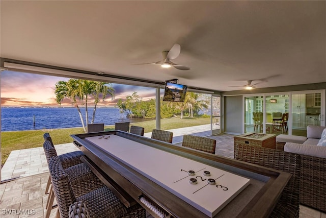 patio terrace at dusk featuring a yard, outdoor lounge area, and ceiling fan