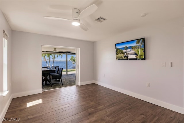 spare room with dark wood-style flooring, visible vents, ceiling fan, and baseboards