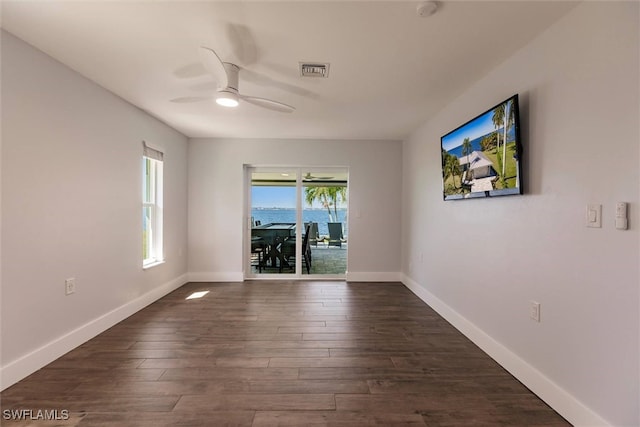 spare room featuring dark wood-style floors, visible vents, ceiling fan, and baseboards