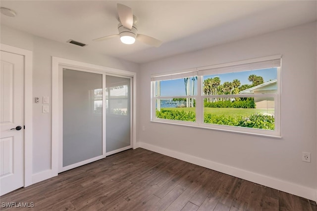 unfurnished bedroom featuring dark wood-type flooring, a closet, visible vents, and baseboards