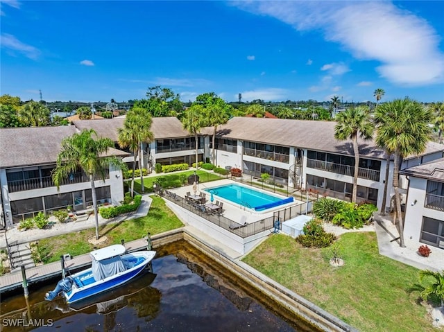 exterior space featuring a patio, a water view, a community pool, fence, and a yard