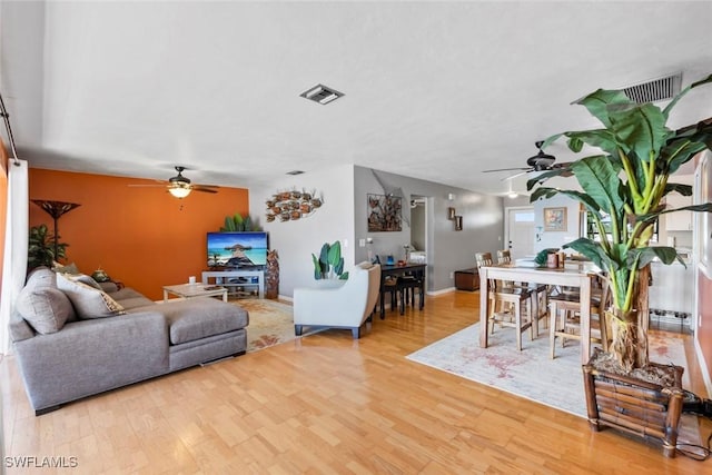 living room with visible vents, ceiling fan, and light wood-style flooring