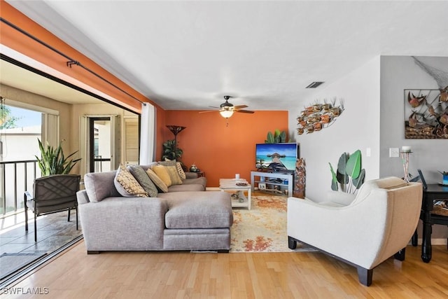 living room with ceiling fan, light wood-style flooring, and visible vents