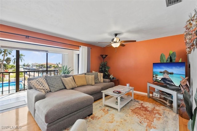 living area featuring a ceiling fan, baseboards, visible vents, and wood finished floors