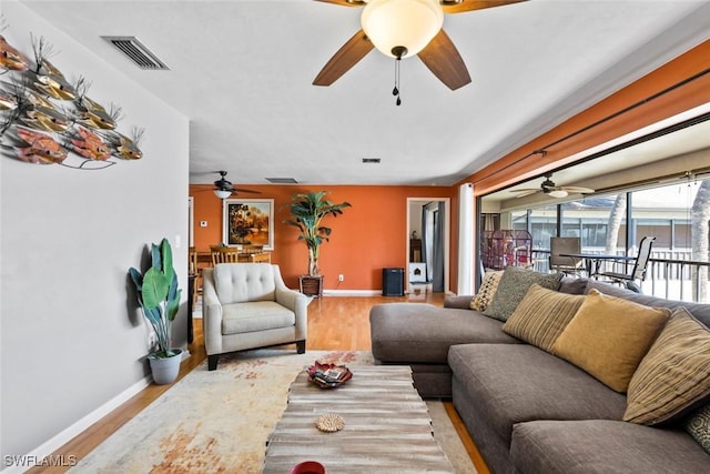 living room featuring a ceiling fan, baseboards, visible vents, and wood finished floors