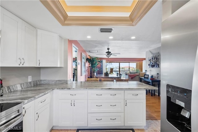 kitchen featuring a raised ceiling, visible vents, range, and a peninsula