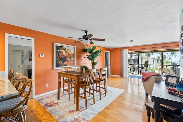 dining space featuring baseboards, ceiling fan, and light wood-style floors