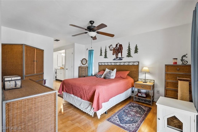 bedroom featuring a ceiling fan, connected bathroom, visible vents, and wood finished floors