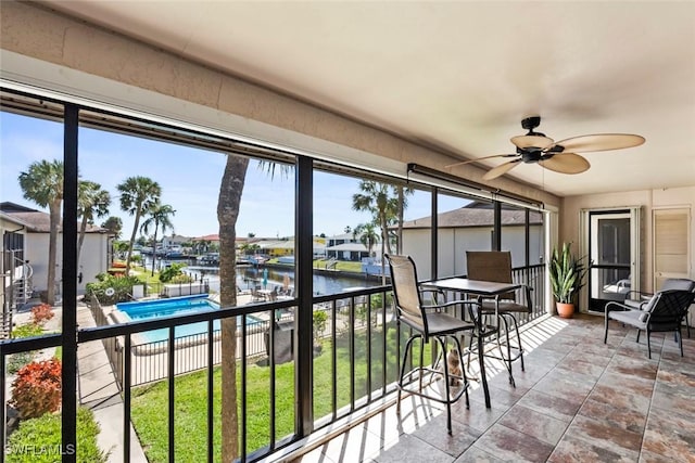 sunroom / solarium featuring a water view and ceiling fan