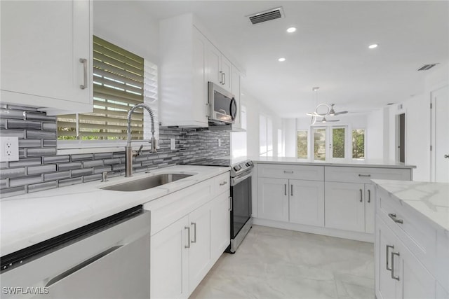 kitchen with stainless steel appliances, tasteful backsplash, visible vents, white cabinetry, and a sink