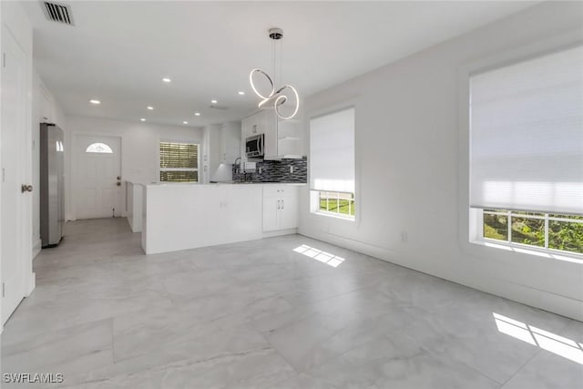 kitchen with visible vents, backsplash, appliances with stainless steel finishes, white cabinets, and plenty of natural light