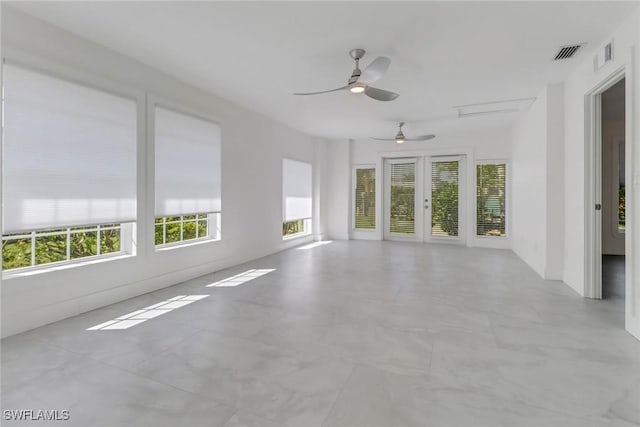 unfurnished sunroom featuring visible vents, a ceiling fan, and french doors