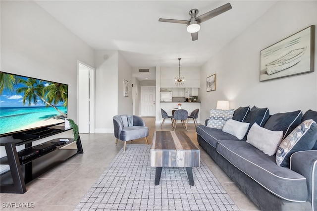 living area with light tile patterned floors, baseboards, visible vents, and ceiling fan with notable chandelier