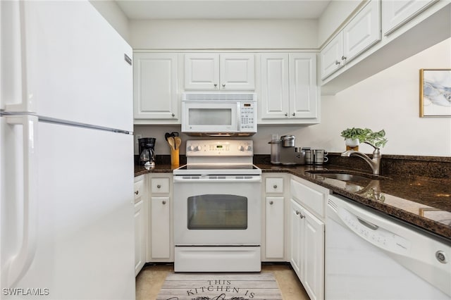 kitchen featuring dark stone counters, white appliances, a sink, and white cabinetry