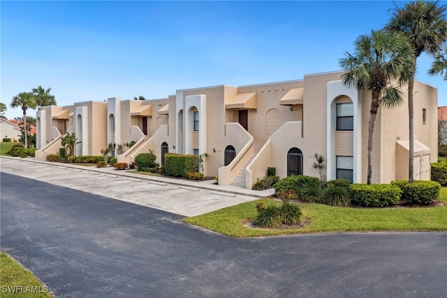 view of front of house featuring uncovered parking, a residential view, and stucco siding