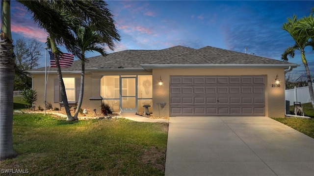 ranch-style home with driveway, an attached garage, fence, a yard, and stucco siding