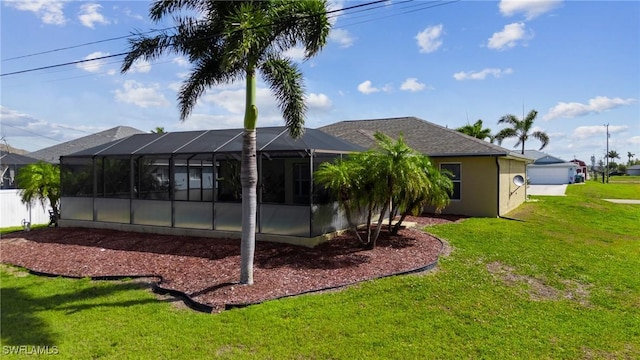 rear view of property with a lawn, a lanai, and stucco siding