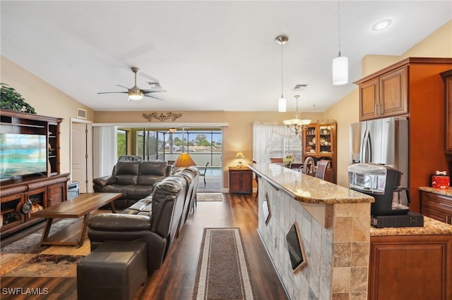 interior space featuring vaulted ceiling, ceiling fan with notable chandelier, wood finished floors, and visible vents