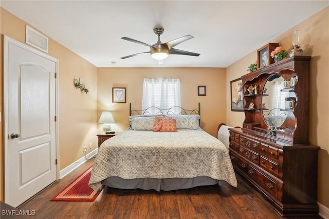 bedroom with a ceiling fan, visible vents, baseboards, and wood finished floors