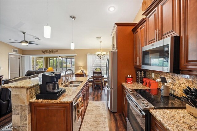 kitchen featuring tasteful backsplash, appliances with stainless steel finishes, open floor plan, light stone countertops, and a sink