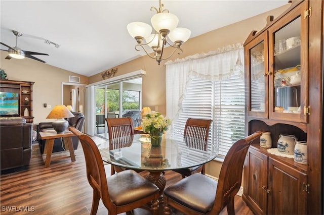 dining area with lofted ceiling, visible vents, dark wood-type flooring, and ceiling fan with notable chandelier