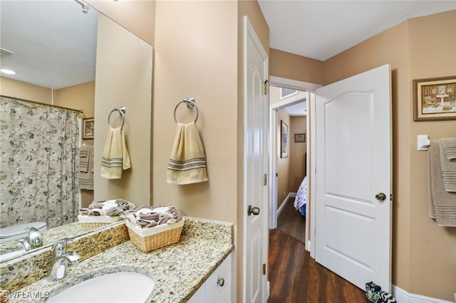 full bath with curtained shower, wood finished floors, vanity, and baseboards