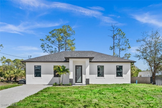 view of front of home with a shingled roof, a front yard, fence, and stucco siding