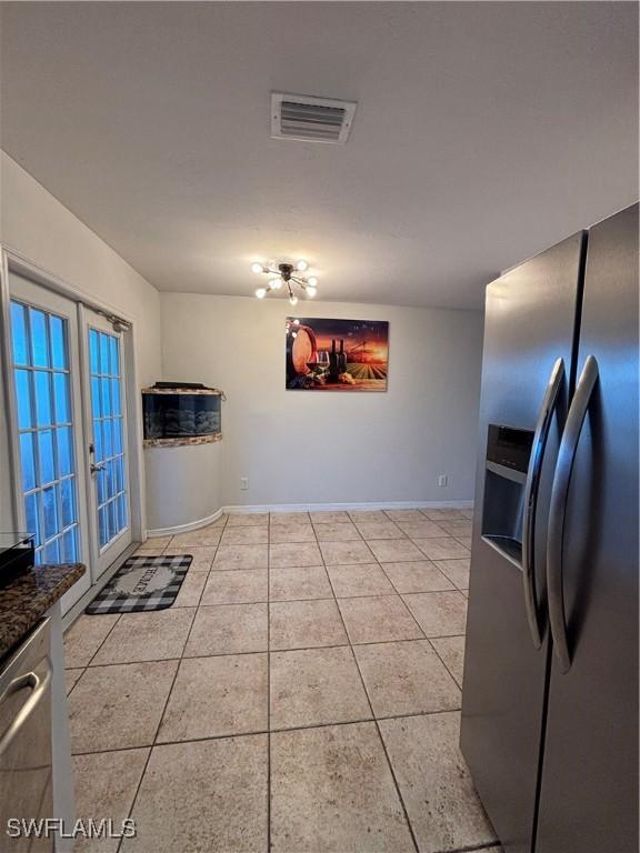 kitchen featuring light tile patterned floors, visible vents, french doors, stainless steel fridge with ice dispenser, and dark countertops