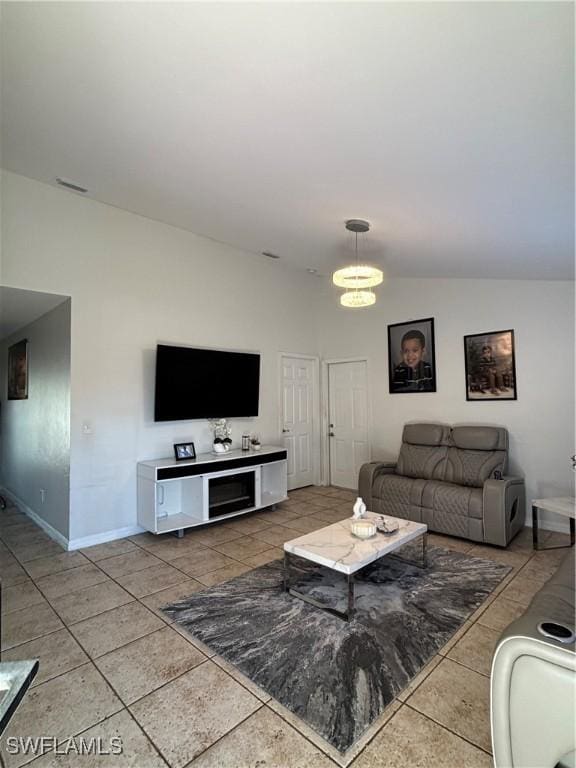 tiled living room with lofted ceiling, baseboards, and a chandelier