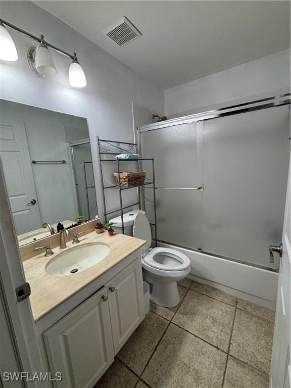 bathroom with toilet, bath / shower combo with glass door, vanity, and visible vents